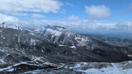 Fototapeta premium Wide scenic panorama of snowy Tatra peaks and rocky slopes under cloudy sky in Poland.