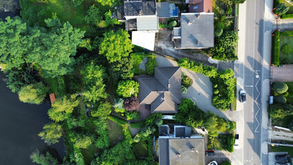 Aerial drone photograph showing residential house, street, and green surroundings in Poland. Urban planning and real estate concept.