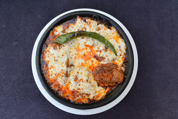 Oven baked meatballs with cheddar on a clay plate

