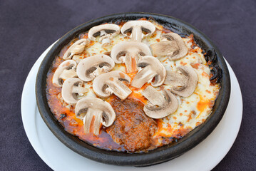 Oven baked mushrooms with cheddar on a clay plate
