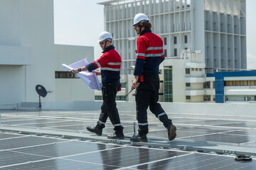 Engineers reviewing solar panel blueprint on rooftop