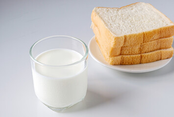 breakfast,Fresh milk in a glass and White sliced bread stacked on the white wooden table