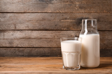 Bottle and glass of fresh milk on wooden background