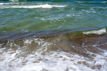 Obraz premium Sea waves green water stormy blue sky beach sand textures