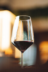 Bottle pouring red wine into elegant glass at bar counter