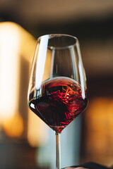 Red wine splash in glass while pouring at restaurant