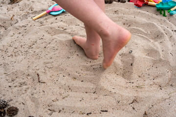 Sand play beach digging pinecones hands feet child playing summer vacation holiday 