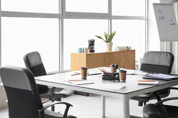 Table, armchairs and stationery prepared for business meeting in conference hall