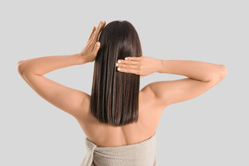 Naklejka premium Beautiful woman in towel after shower on light background, back view