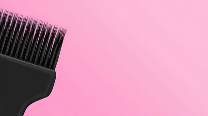 Black hairbrush with fine bristles positioned against a soft pink background, showcasing a minimalist design and vibrant color contrast for beauty and grooming concepts