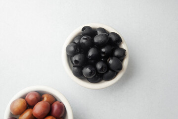 Variety of olives in bowls with wooden spoons on gray background, green olives, black and kalamata olives.