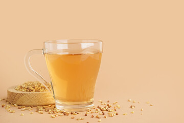 Glass cup of tasty buckwheat tea on beige background