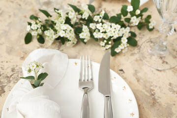 Beautiful table setting with plate, cutlery, napkin and blooming branches on grunge background, closeup
