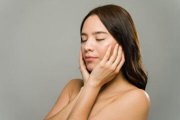Beautiful woman touching face with glowing skin in studio shot © AntonioDiaz