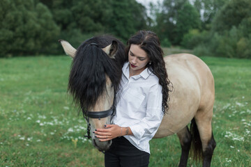 young woman in a white shirt embraces her horse in a green meadow, symbolizing love, care, and harmony between humans and animals, perfect image of friendship and countryside lifestyle