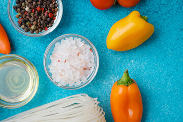 various cooking ingredients with noodles and vegetables on blue background