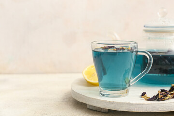 White wooden tray with cup of butterfly pea flower tea on light background, closeup