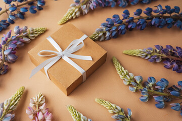 Gift box and lupine flowers on beige background