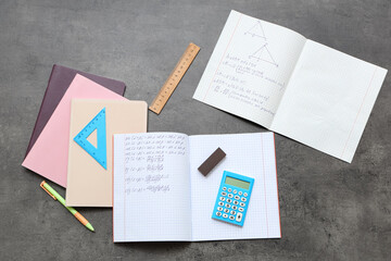 Copybooks with math formulas, books and stationery on dark background