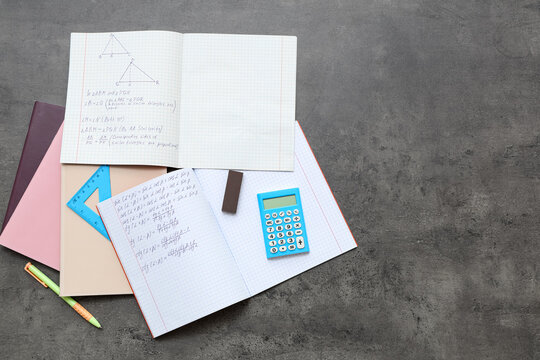 Copybooks with math formulas, books and stationery on dark background - Powered by Adobe