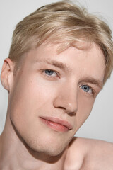 Obraz premium Portrait of young man with soft gaze and clean glowing skin. Concept of skincare, grooming, natural beauty, cosmetics branding, wellness lifestyle and personal care.