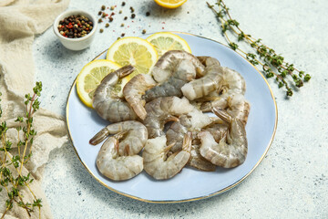 Plate with fresh raw shrimps and lemon on white background