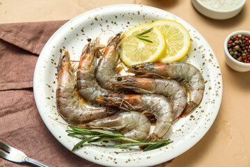 Plate with fresh raw shrimps, lemon and rosemary on beige background