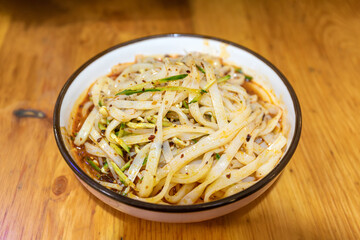 Cold noodles snack in a porcelain bowl on a wood-grained table