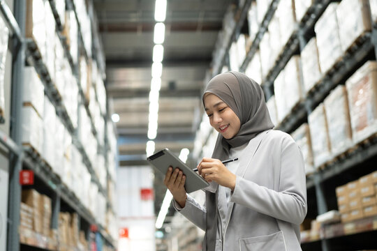 Muslim female warehouse worker holding digital tablet checking inventory in warehouse