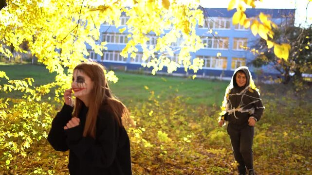      Teenage friends with stage makeup of a mime during an acting lesson celebrate Halloween in the park near the school, act out scenes and having fun