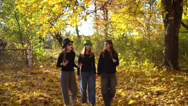      Teenage friends with stage makeup of a mime during an acting lesson celebrate Halloween in the park near the school, act out scenes and having fun