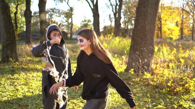      Teenage friends with stage makeup of a mime during an acting lesson celebrate Halloween in the park near the school, act out scenes and having fun