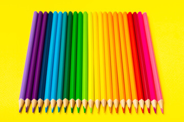 Fototapeta premium Colored pencils on a bright colored background. Equipment for coloring. Stationery for creativity.Back to school. Flatlay. Children's Creativity and Education. Rainbow.Space for text. Copy space.
