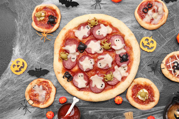 Composition with tasty Halloween pizzas, decorations and spiderweb on dark background