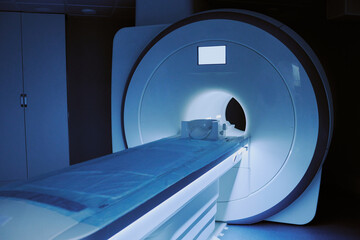 MRI scanner standing in medical imaging room with empty patient table extending toward large circular opening, advanced diagnostic equipment prepared for radiology examination