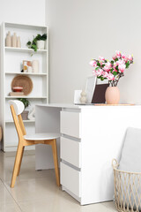 Vase with magnolia flowers on desk in light room