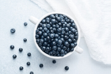 Blueberries in white bowl with soft cloth for comfort, diet or organic eating concept