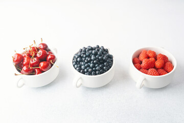 Bowls of raspberries, blueberries and cherries for fruit trio, diet or nutrition concept