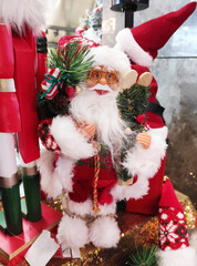 A Christmas toy in the form of Santa Claus with a white beard and glasses, wearing a hat and coat.  The atmosphere of celebration, comfort and winter fun. A holiday card for the New Year holiday.