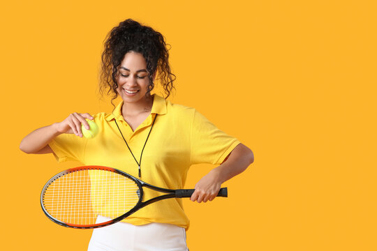 Female African-American tennis trainer with racket and ball on yellow background