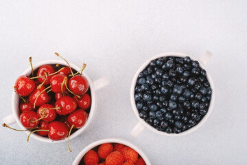 Three fruit bowls (cherries, blueberries, raspberries) on white for wellness or shared snack concept