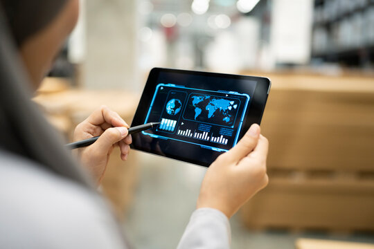Rear view of Muslim female warehouse worker analyzing business data on tablet PC in warehouse - Powered by Adobe