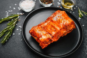 Spicy pork ribs on black plate with rosemary and salt