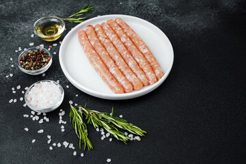 Fresh pork sausages on white plate with herbs and seasonings