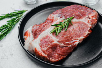 Pork steak with rosemary on black plate with spices