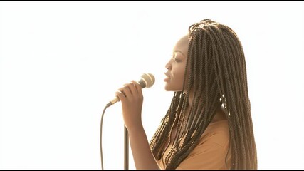 Young woman with long box braids singing softly into microphone - Powered by Adobe