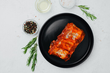 Spicy pork ribs on black plate with seasoning and herbs