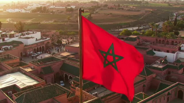 Red Moroccan flag above terracotta buildings at golden hour