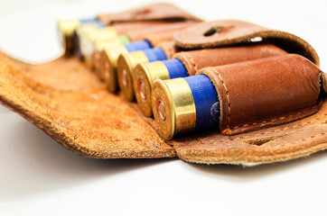 Shotgun shell carrier holds worn rounds of blue, gold, and red in rustic leather holder showcasing texture and craftsmanship. Well-used container displays vintage appeal, perfect for highlighting