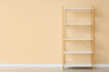 Empty white bookshelf near beige wall